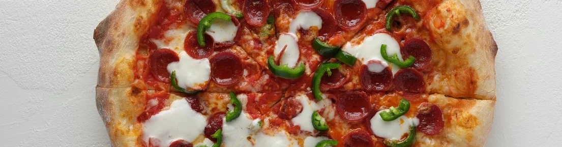 Pepperoni pizza with green peppers on a wooden peel
