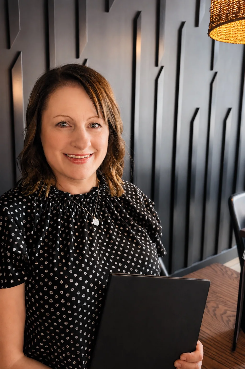 Smiling woman holding a menu in a modern restaurant setting.