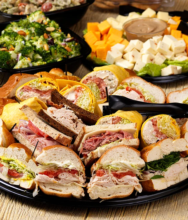 Gourmet sandwich platter from Isaac's Craft Kitchen & Brewery, featuring assorted deli sandwiches, wraps, fresh veggies, and artisan bread, served with broccoli salad and a cheese tray. Perfect for catering and events.