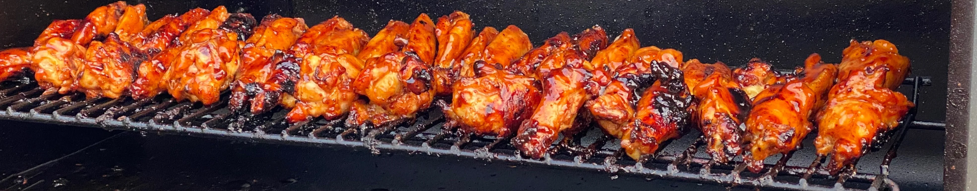 Grilled barbecue chicken wings on a smoker rack