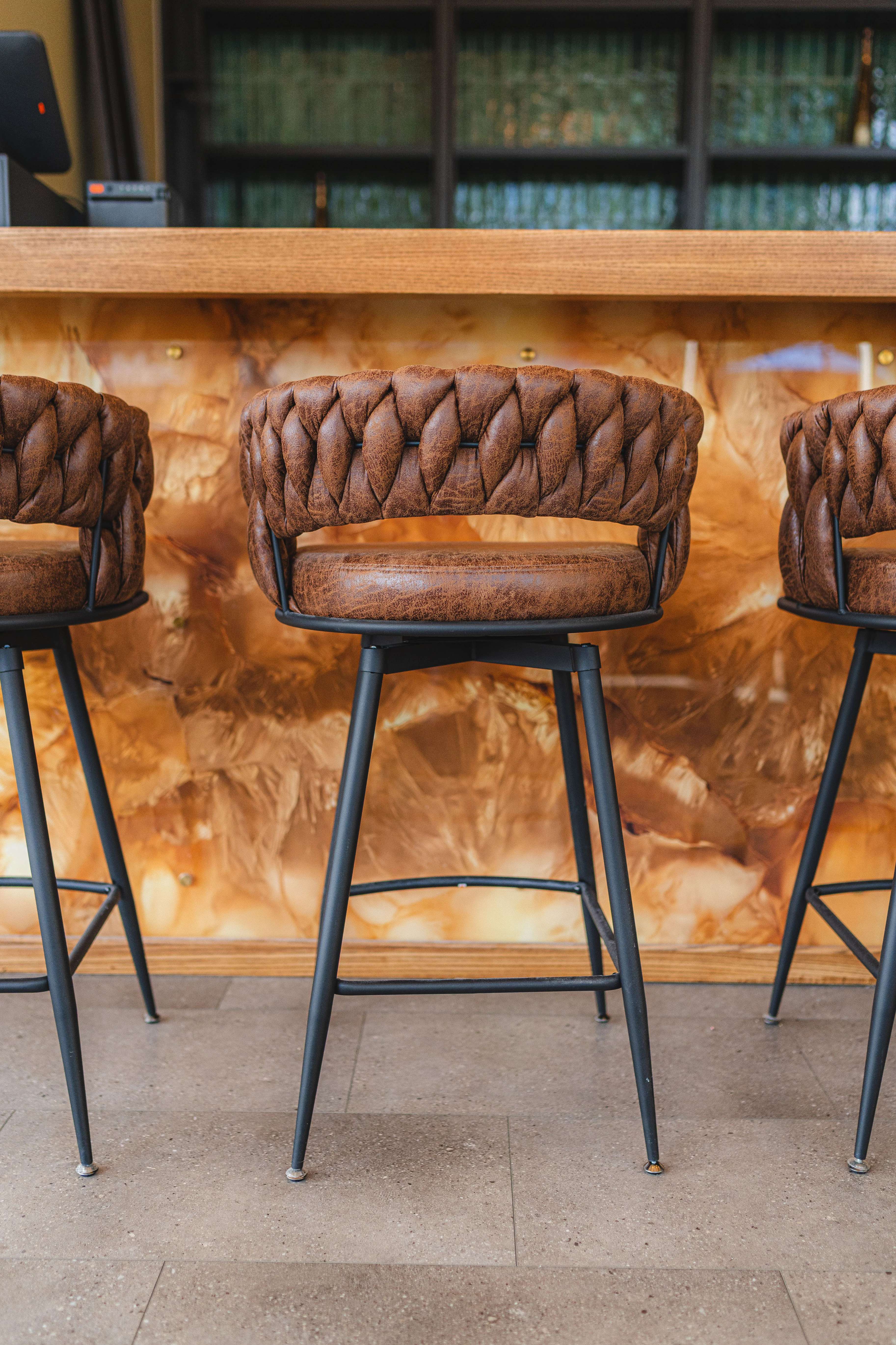Stylish bar stools with woven leather design at a modern restaurant counter