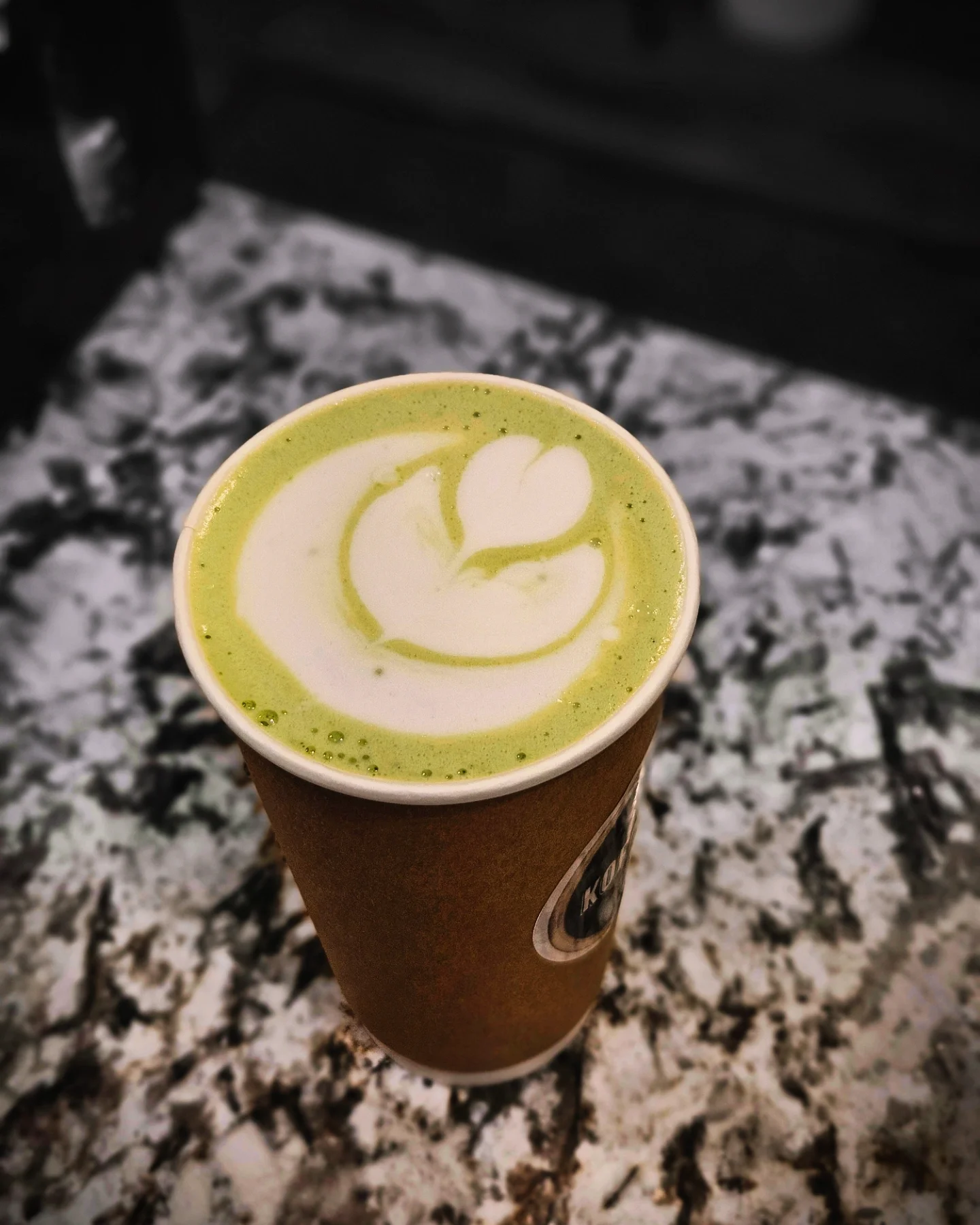 Matcha latte with latte art in a paper cup