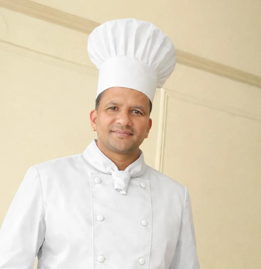 Chef in a white uniform and hat posing confidently