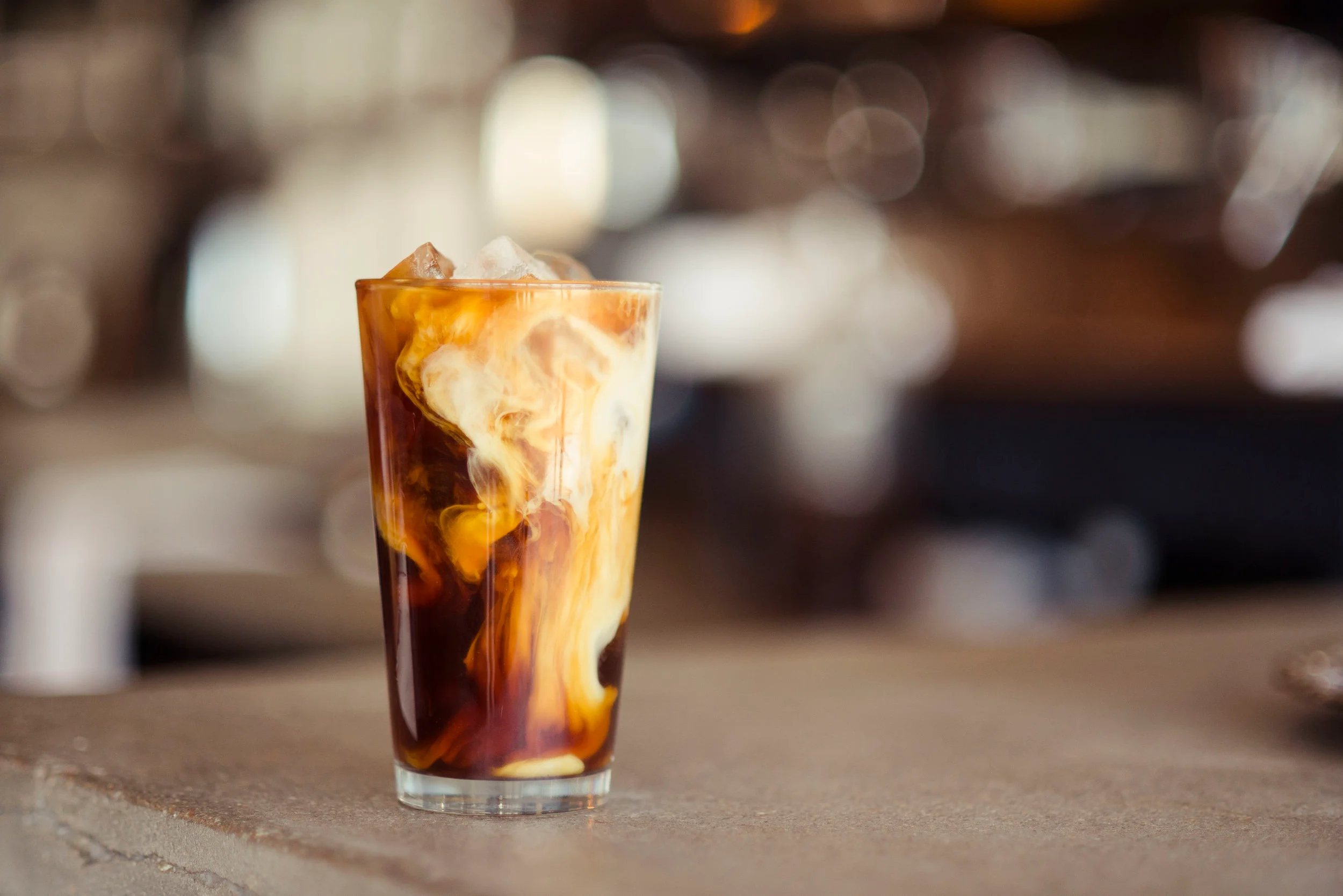 Iced coffee with cream swirling in a glass