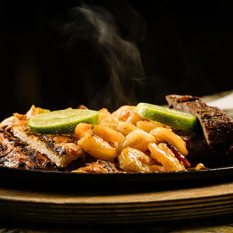 Sizzling fajitas with grilled shrimp and lime wedges