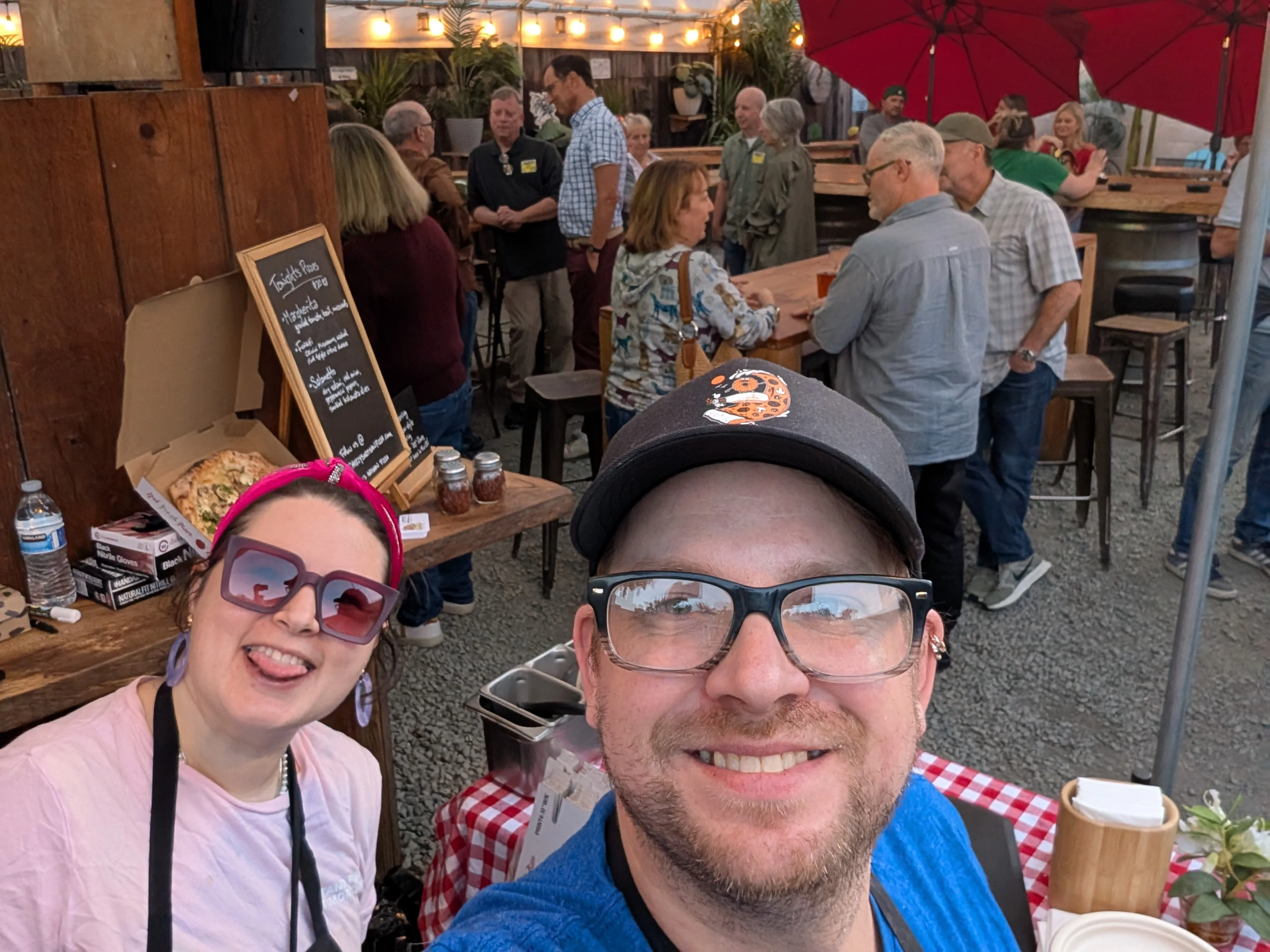 Casual restaurant gathering with diners, outdoor seating, and pizza