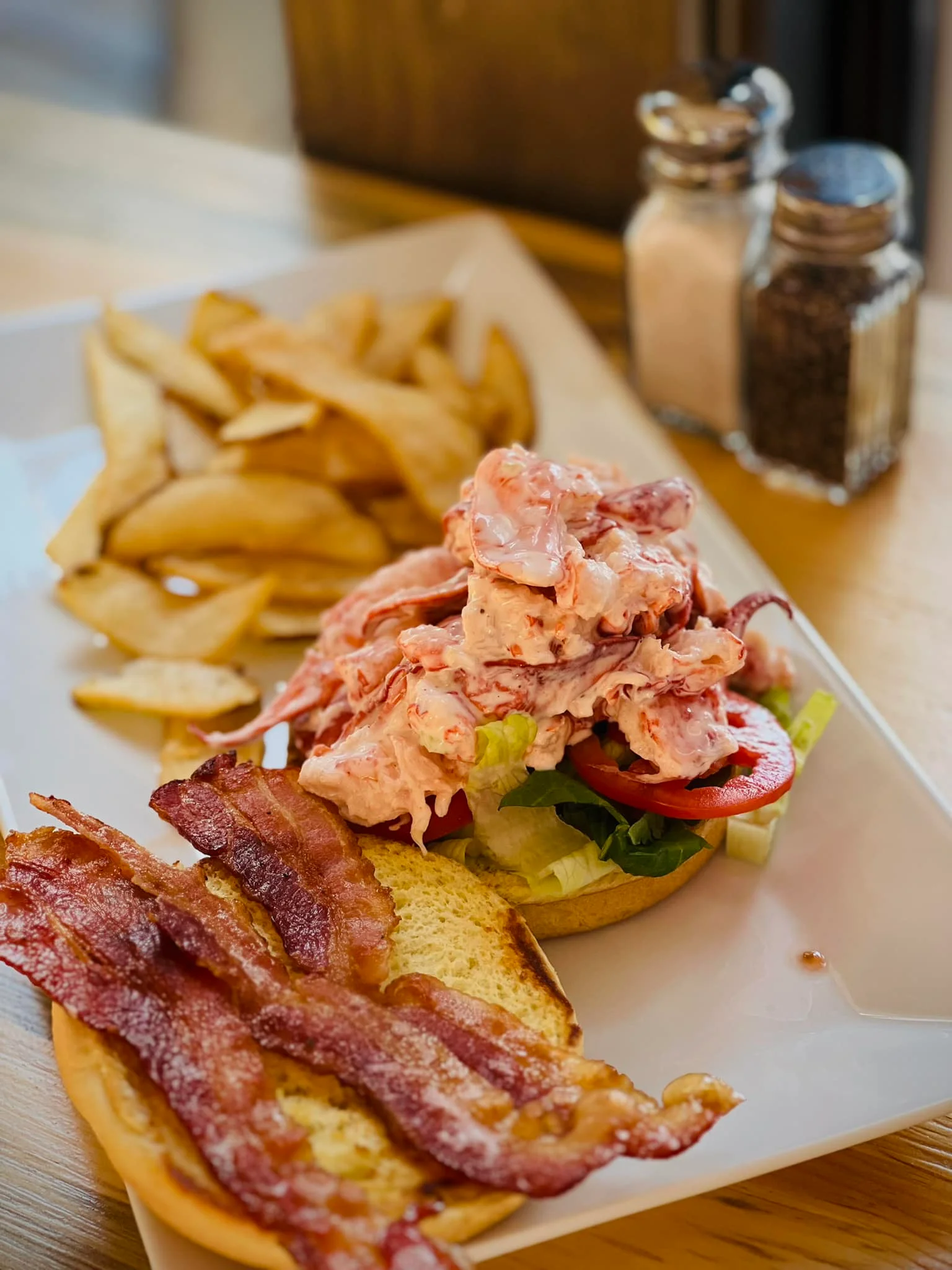 Lobster roll with crispy bacon and fries