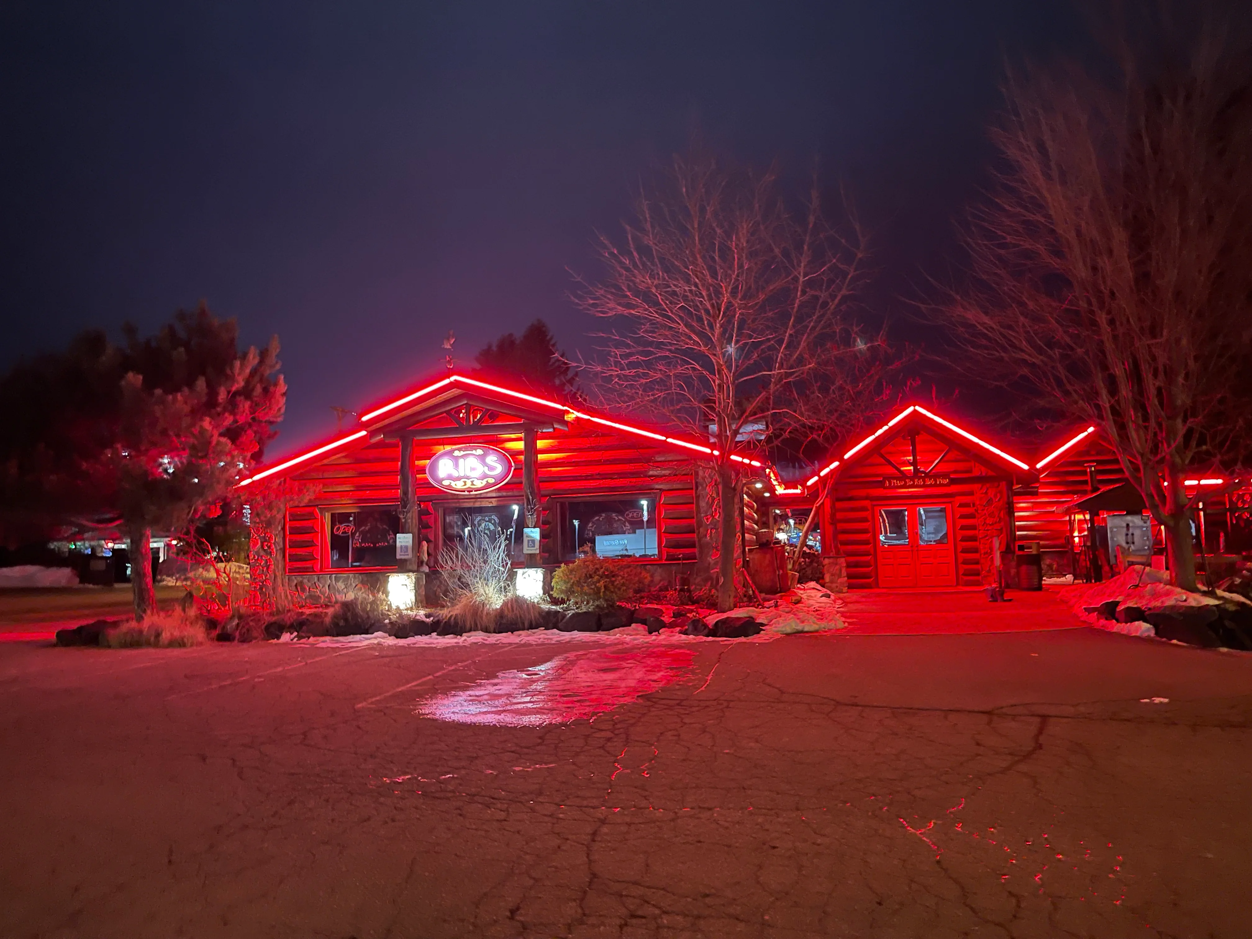 Cozy log cabin restaurant illuminated with red neon lights at night