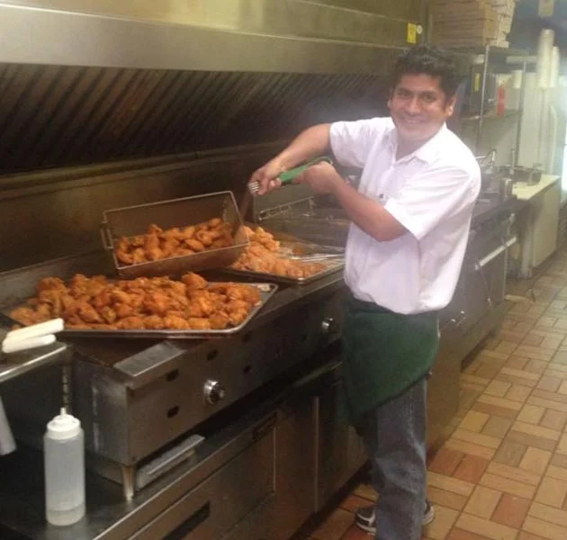 Chef preparing crispy fried chicken in a busy kitchen