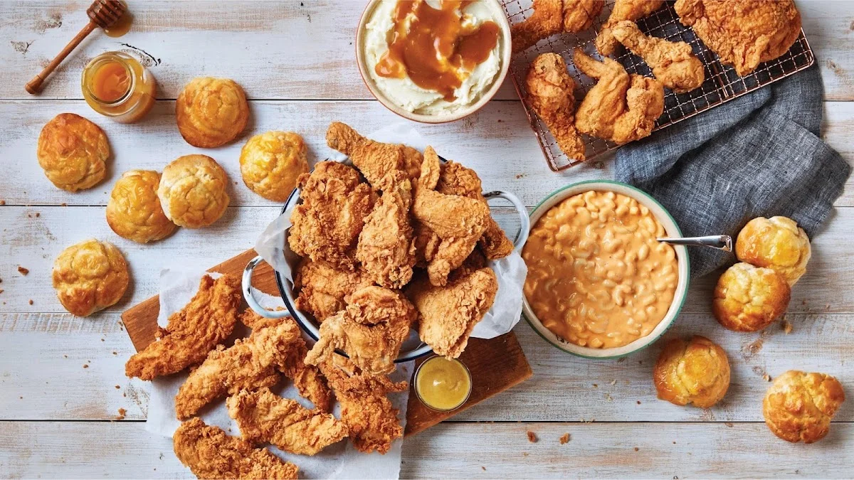 A spread of fried chicken, biscuits, macaroni, and gravy on a wooden table.