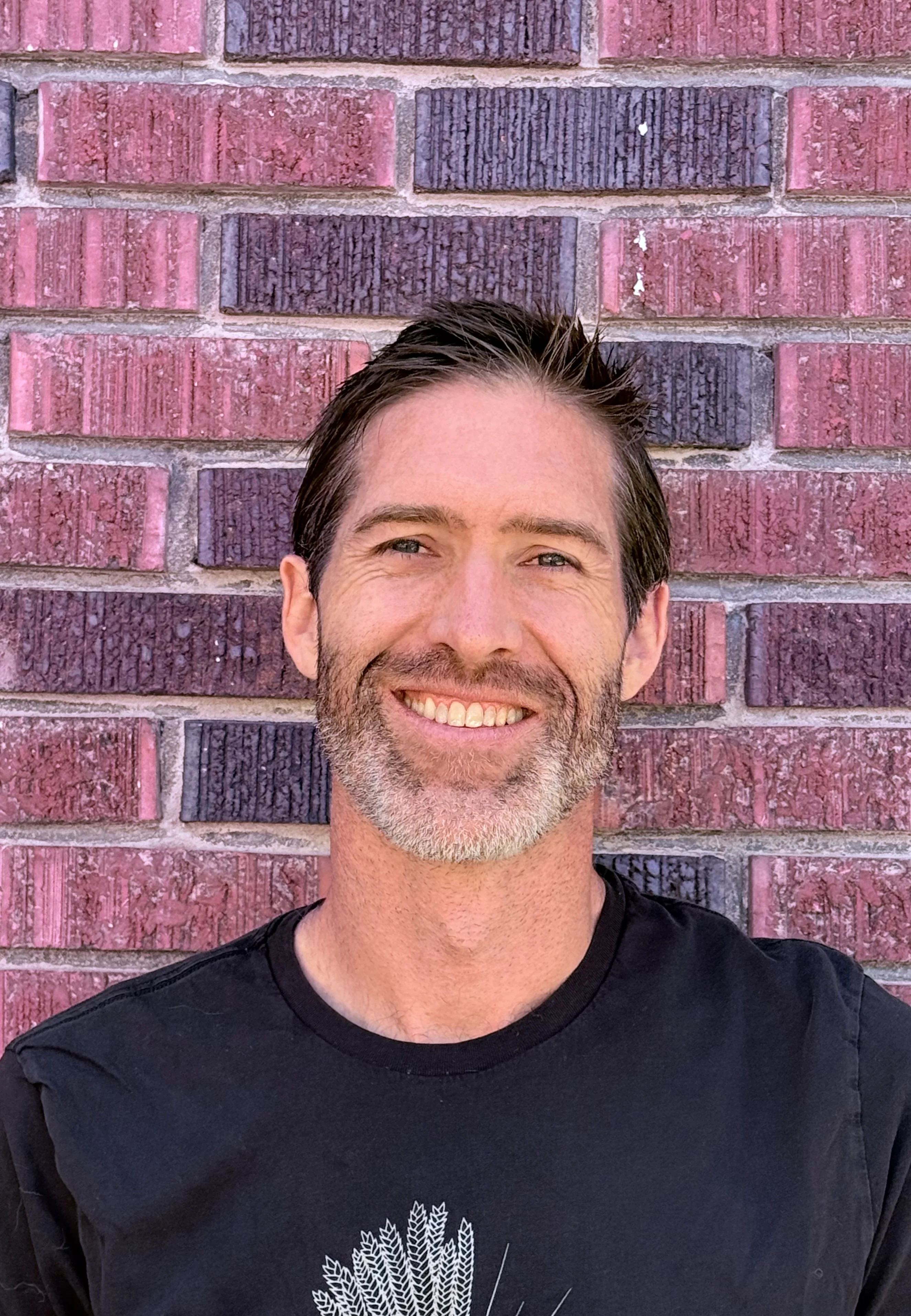 Smiling man in front of a brick wall