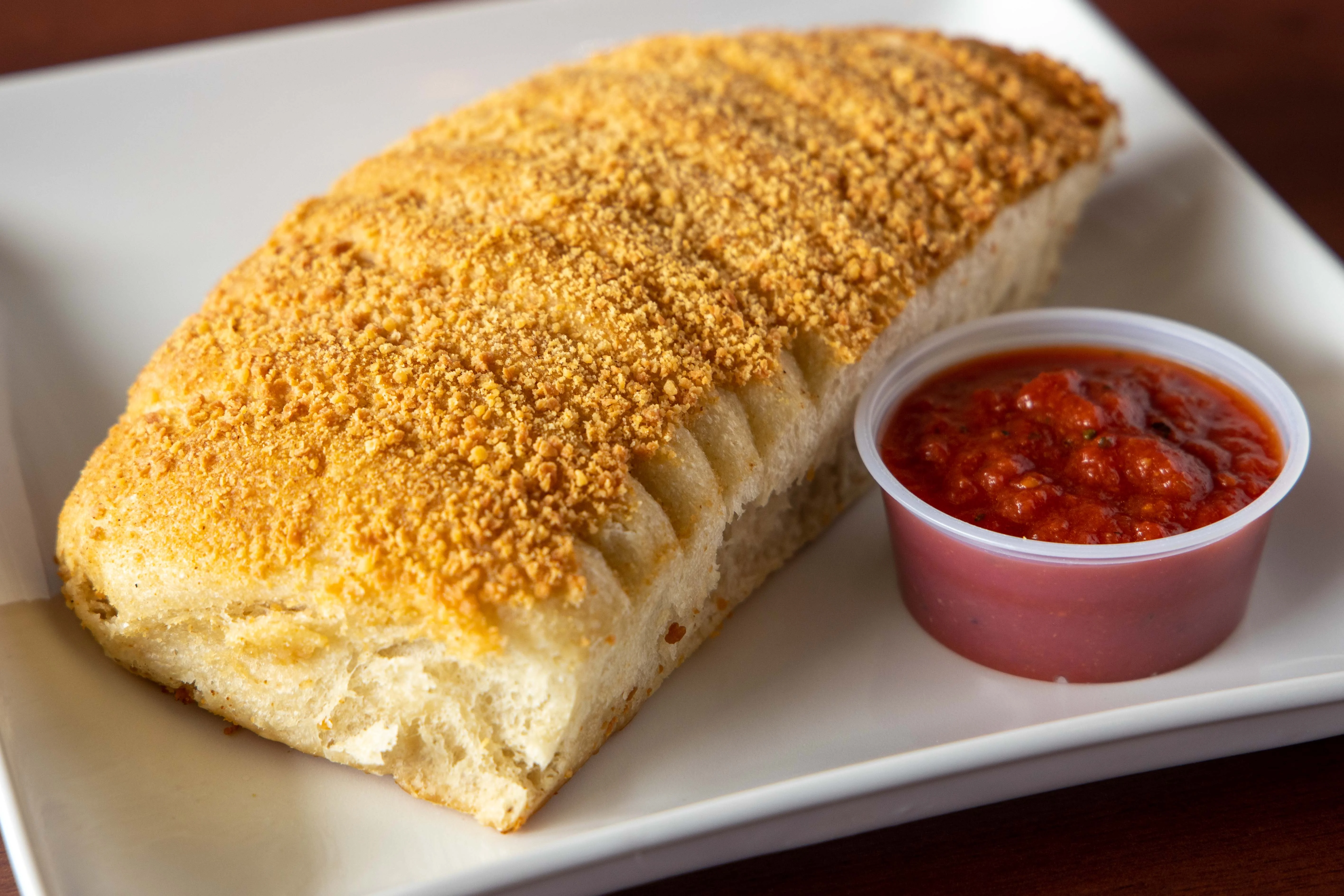 Golden-brown calzone served with marinara sauce