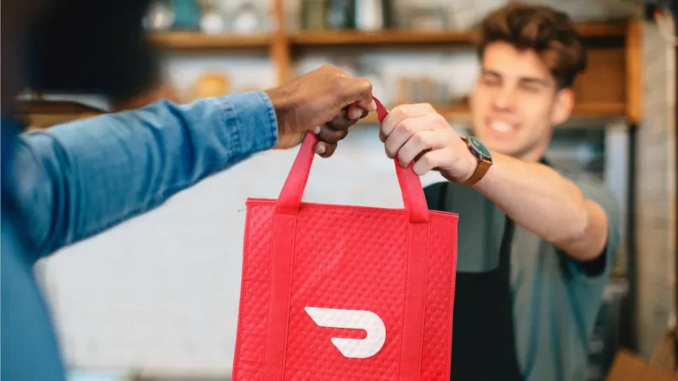 Delivery person handing over a red food delivery bag