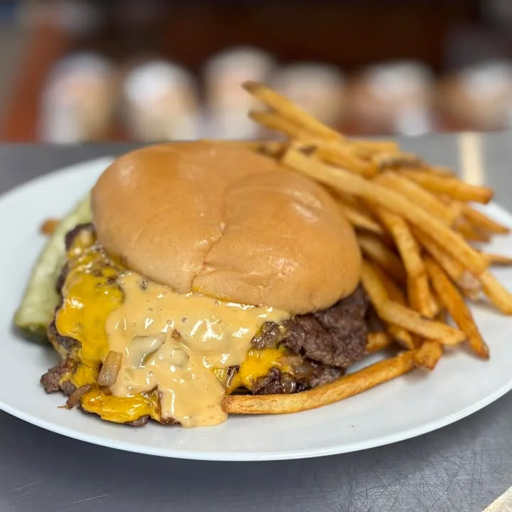 A cheesy beef burger topped with fresh lettuce, tomato, and onion slices, served in a soft bun.