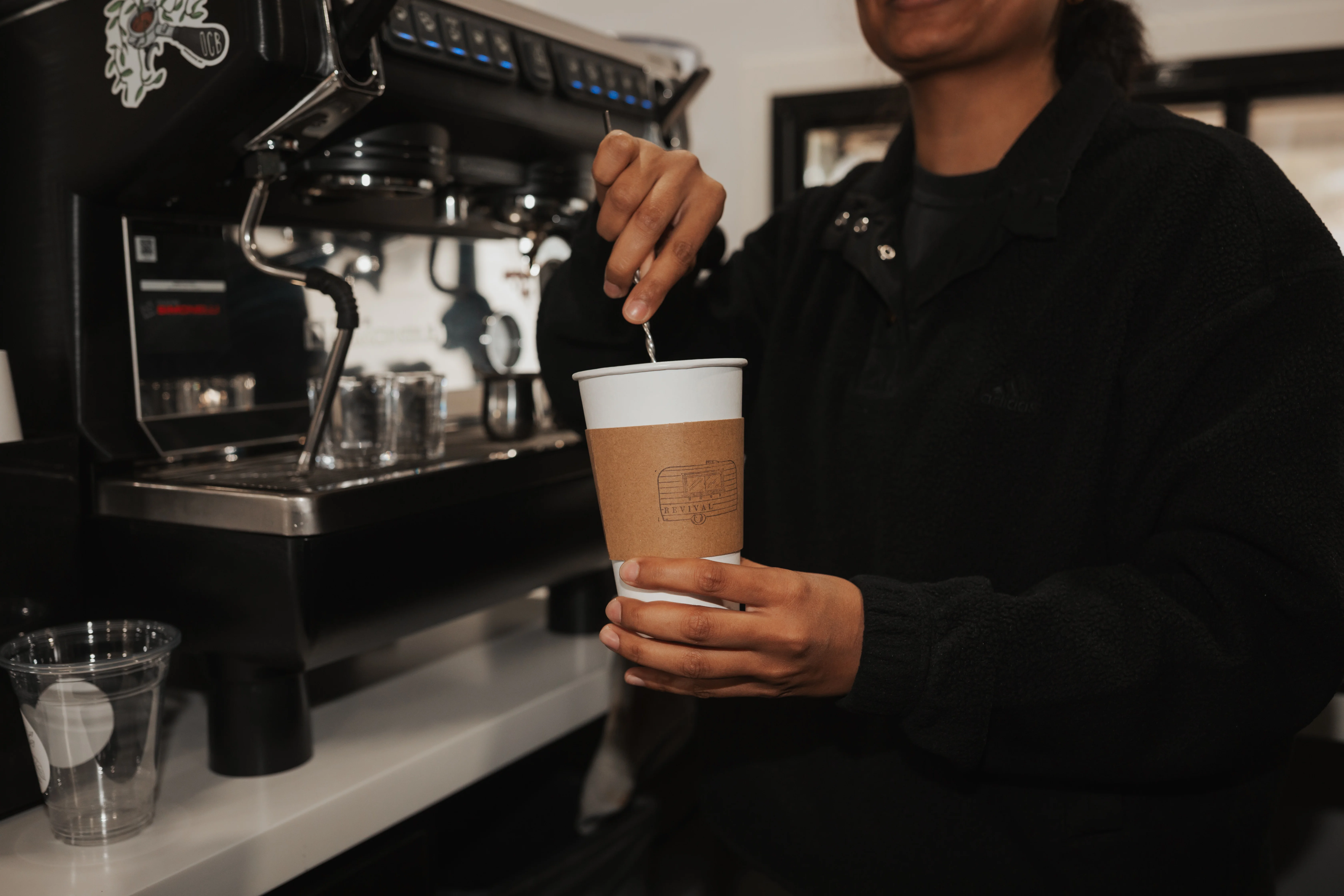Revival Coffee stirring home-made syrups in a hot latte.