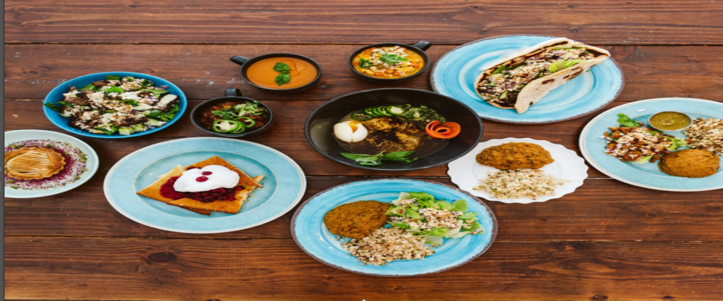 Assorted Indian dishes including curry, salad, and dessert on wooden table