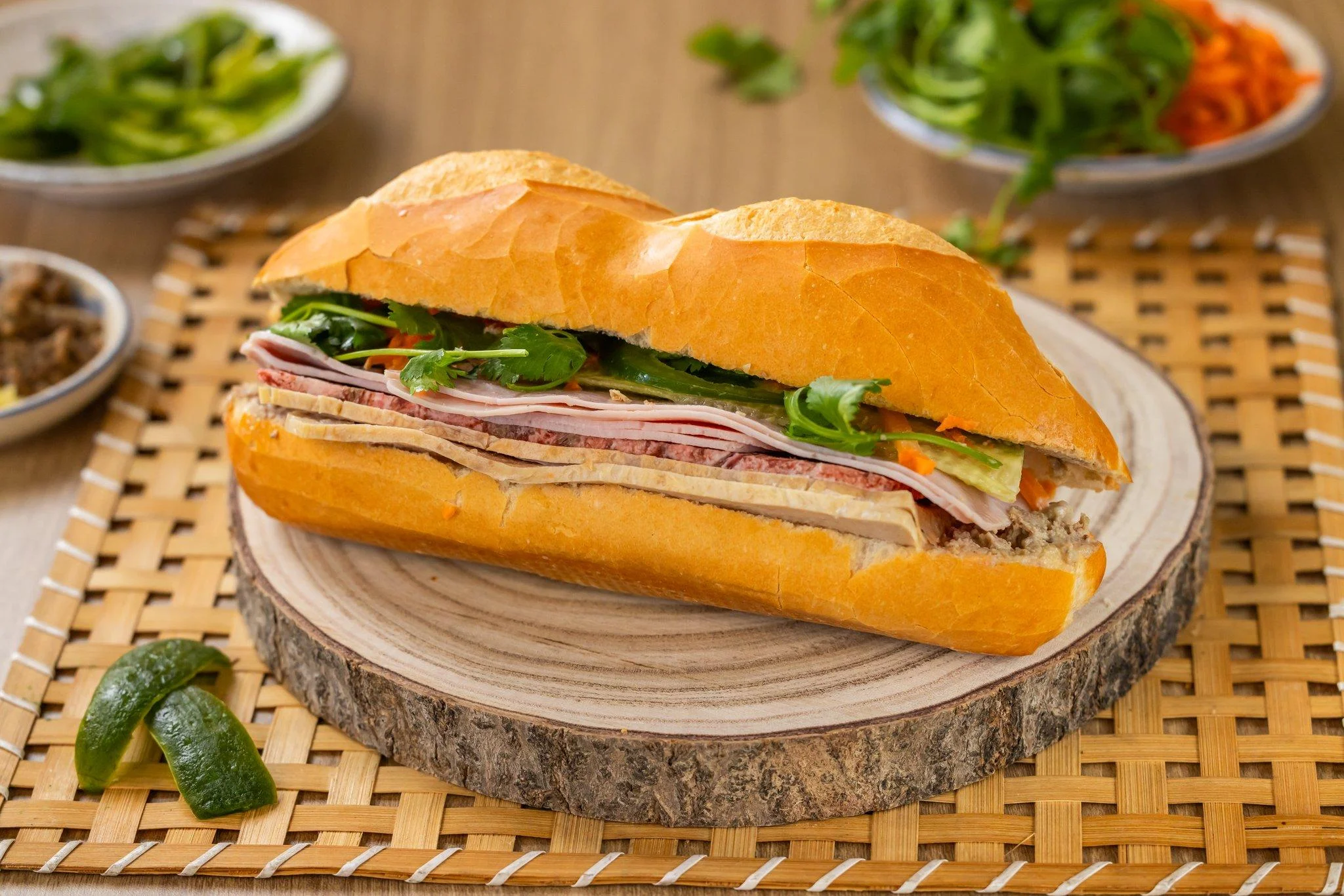 A sandwich filled with various meats, fresh herbs, and vegetables, served on a crusty baguette.