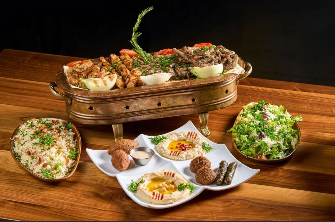 A combo meal containing hummus with ganough, large tzatziki, 8 kibbeh, 8 grape leaves, pita, and more at Sufrat Grill.