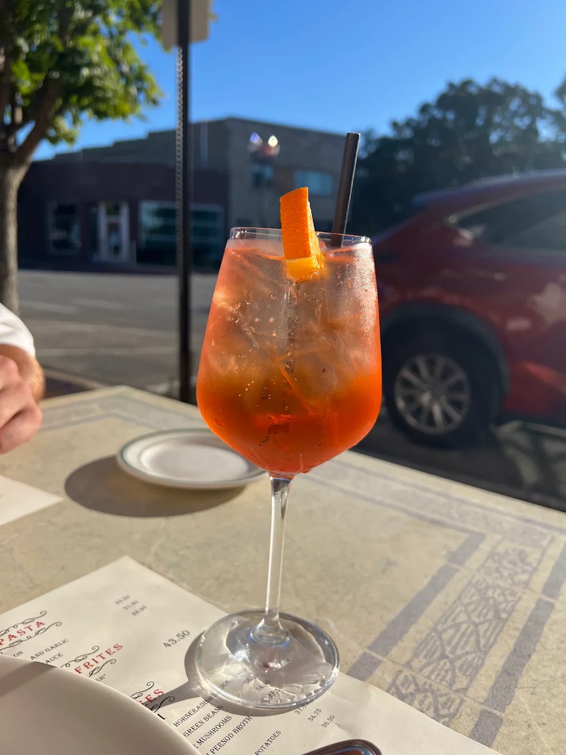 Refreshing cocktail with orange garnish in a sunny outdoor setting