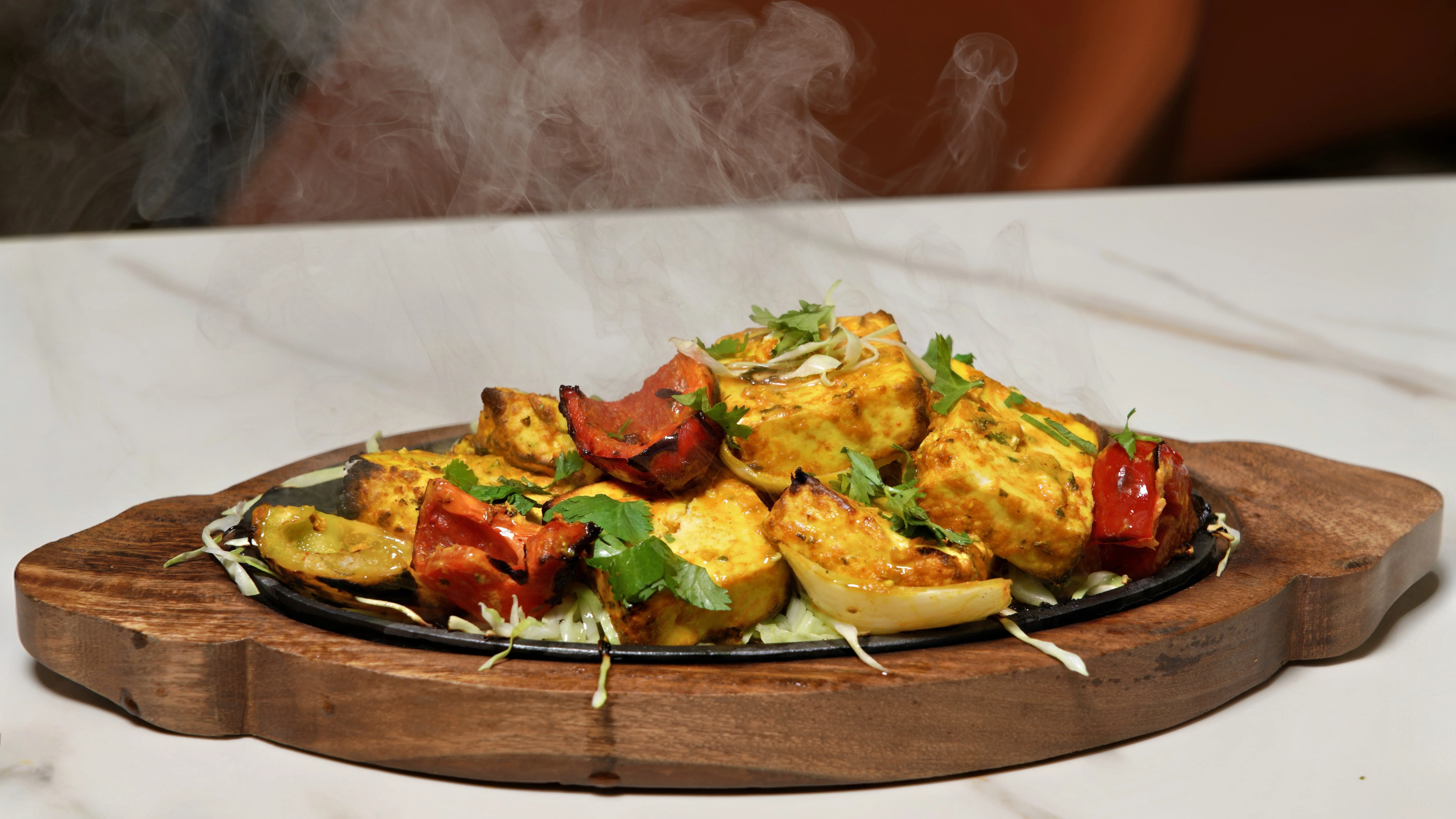 A bowl of biryani featuring yellow and white rice, spices, garnished with an egg and herbs, served in a decorative metal bowl.