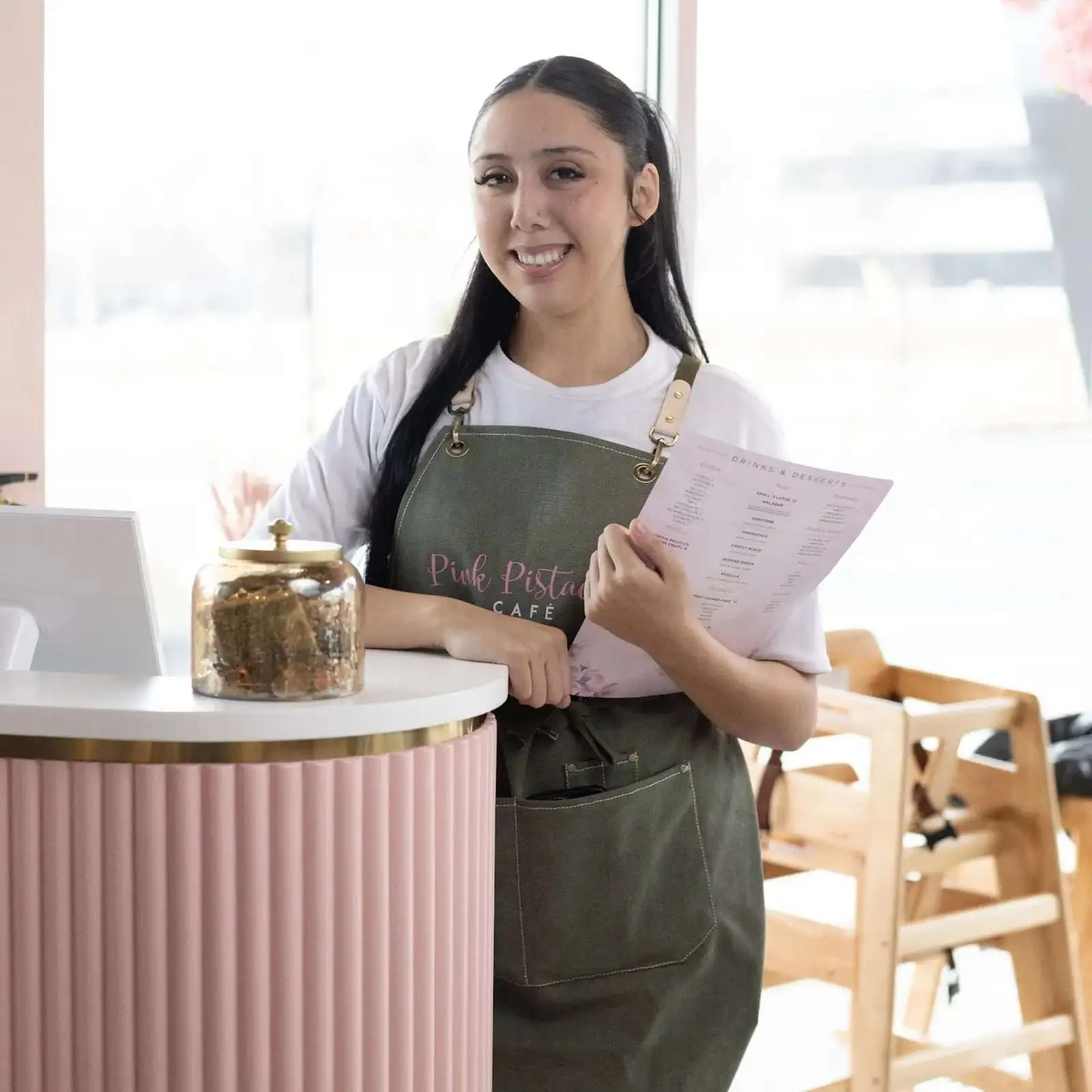 Friendly barista at Pink Pistachio Café with menu