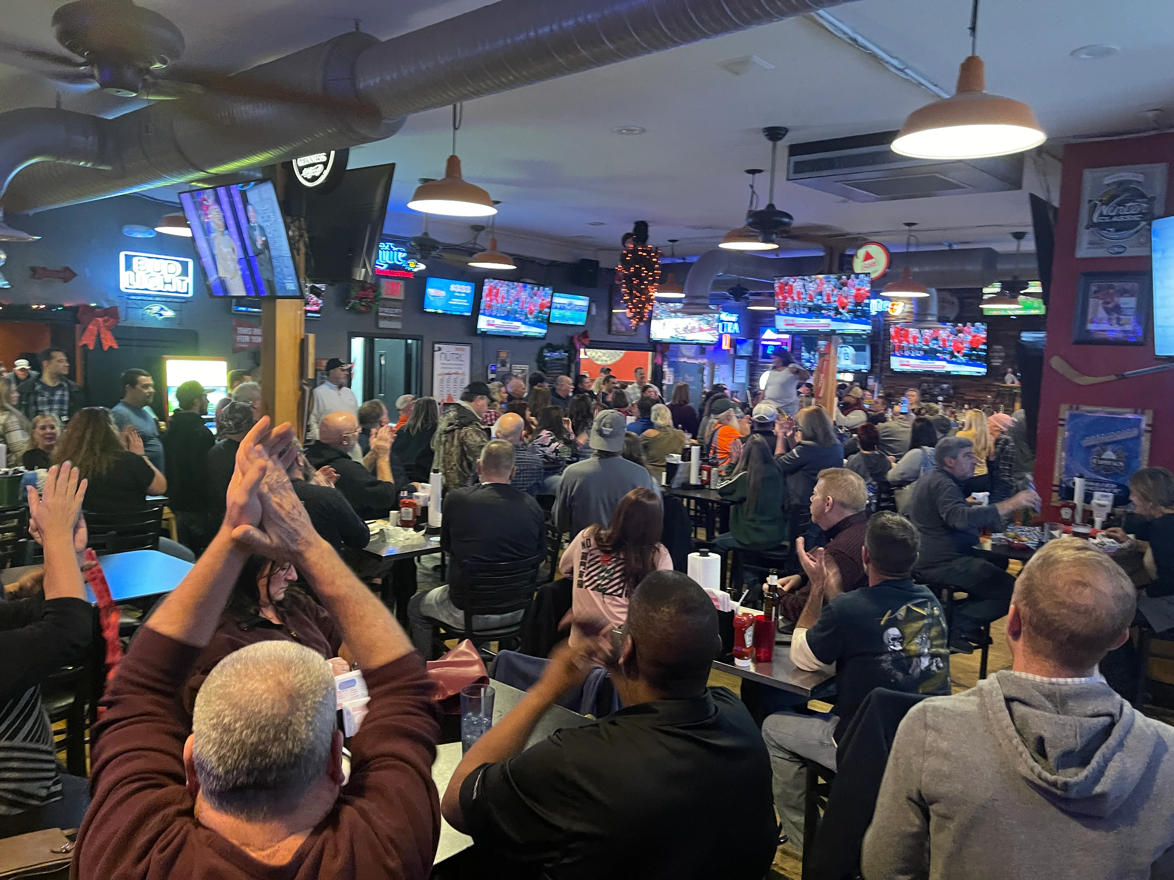 Busy restaurant dining room filled with guests and televisions