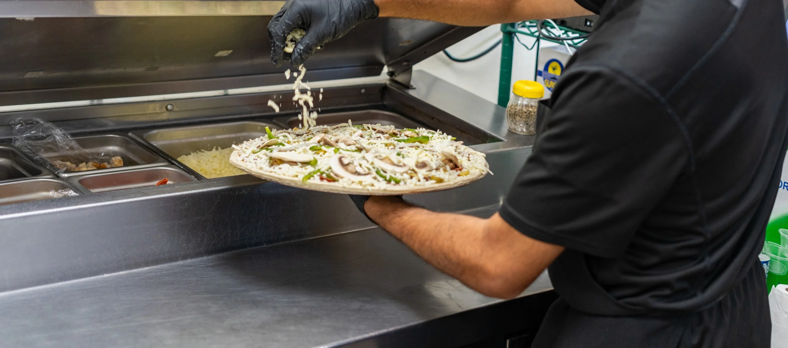 Pizza being prepared with fresh toppings in a restaurant kitchen