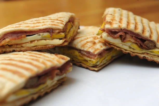 Breakfast sandwich with eggs and ham on toasted flatbread