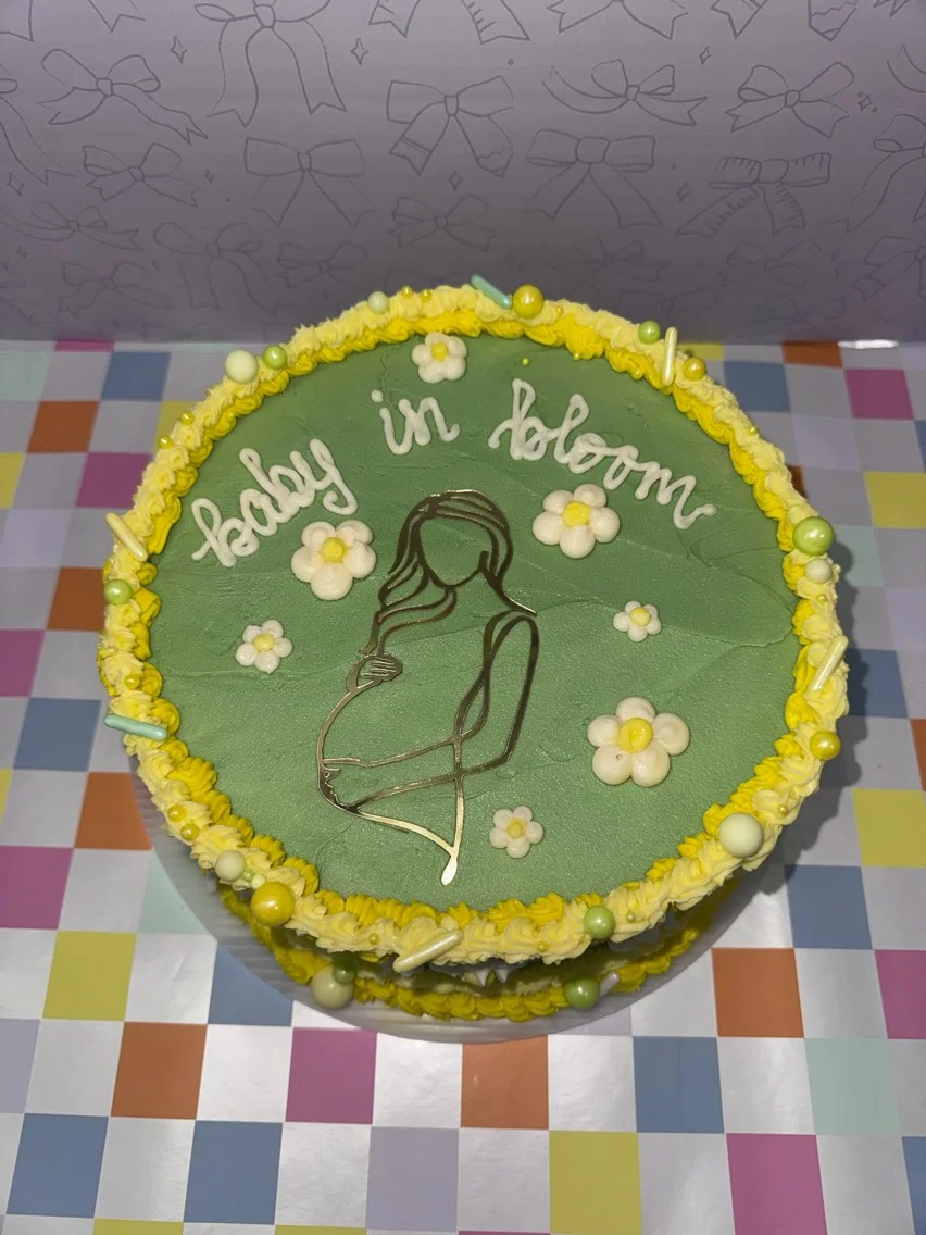 Decorative cake with green frosting and floral accents for a baby shower celebration