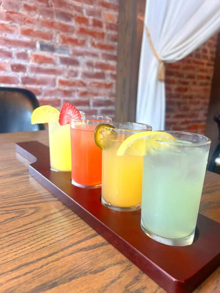 Colorful flight of refreshing cocktails on a wooden tray