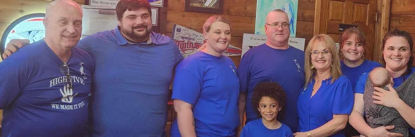Group of people in blue shirts posing inside a restaurant.
