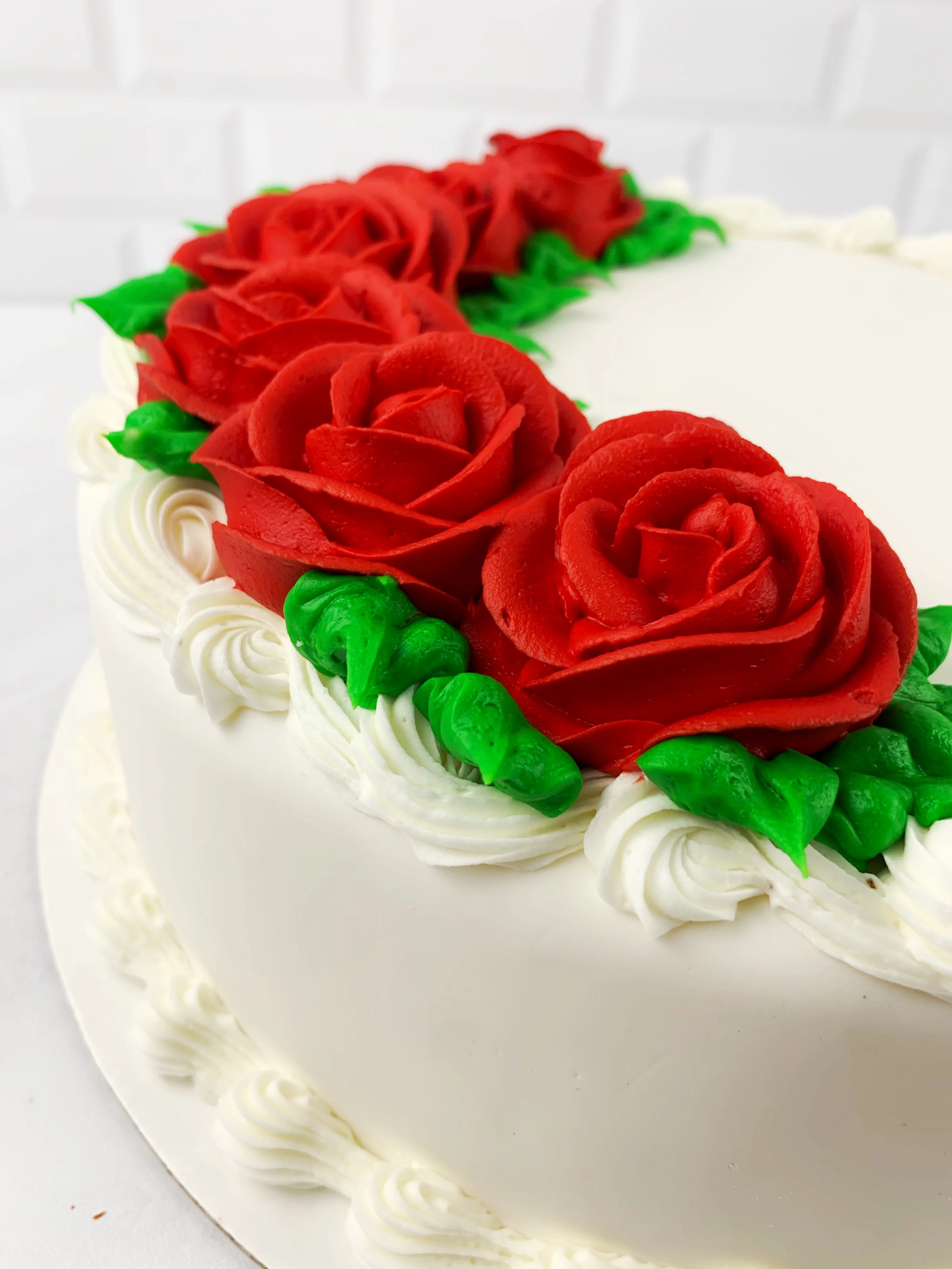 Elegant white cake adorned with red rose decorations