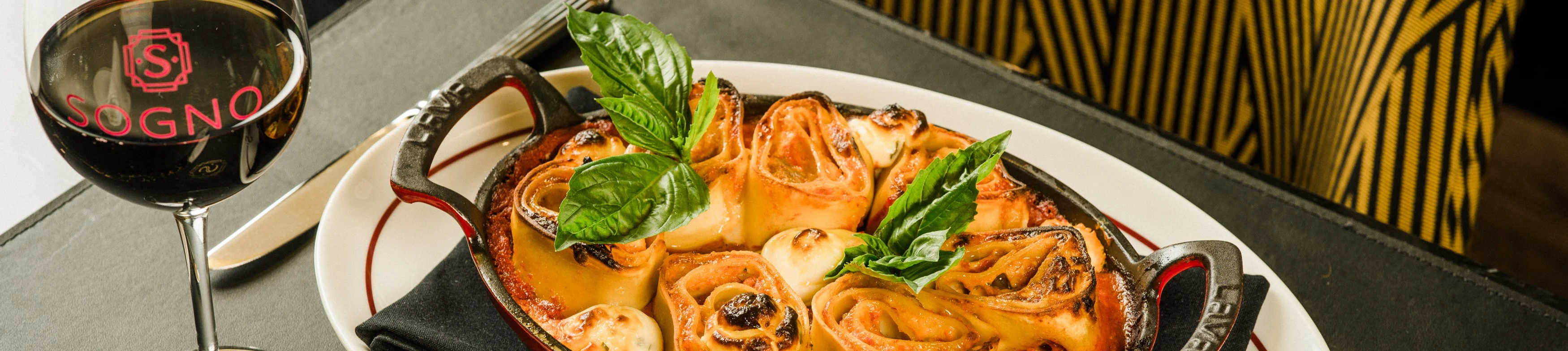 Italian lasagna served in a cast iron dish with fresh basil garnish