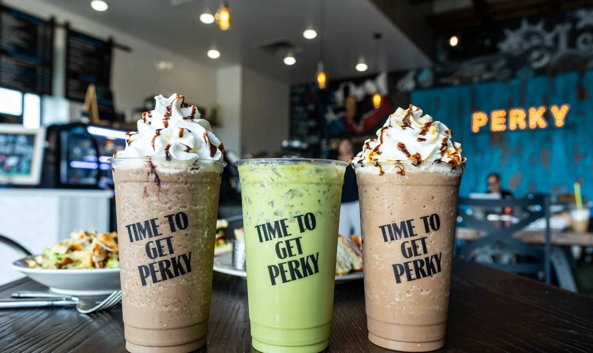 Three colorful iced beverages in a cozy café setting