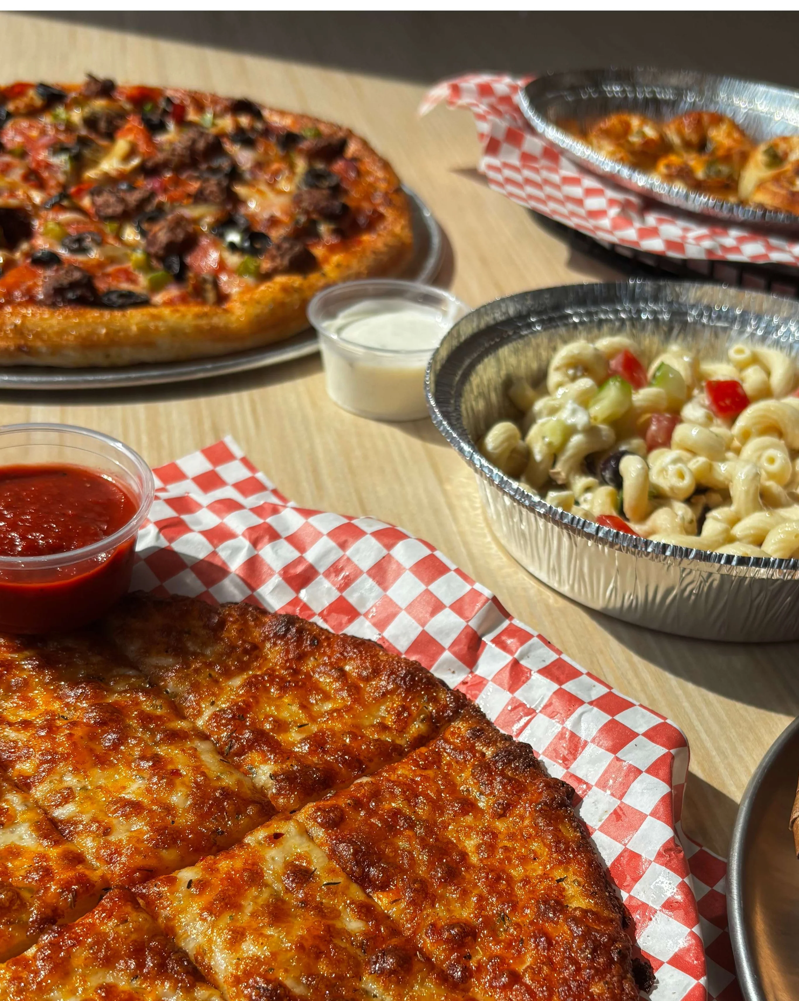 Cheese pizza with marinara sauce and pasta salad in a casual dining setting