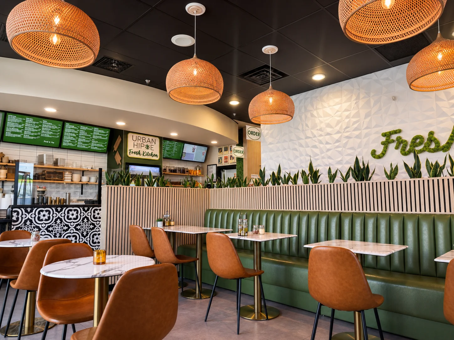 Modern restaurant interior with green seating and pendant lights.