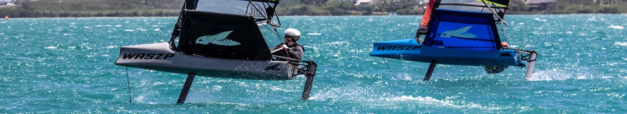 Two WASZP foiling sailboats racing on turquoise waters