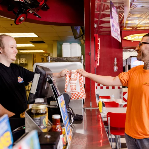 Customer receiving takeout from a vibrant fast-food counter