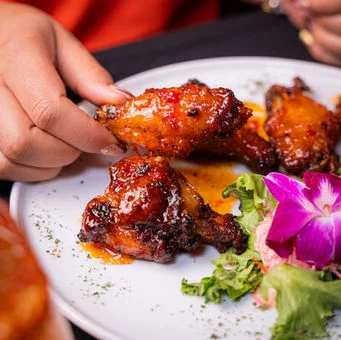 Sticky Asian-style chicken wings with vibrant garnish