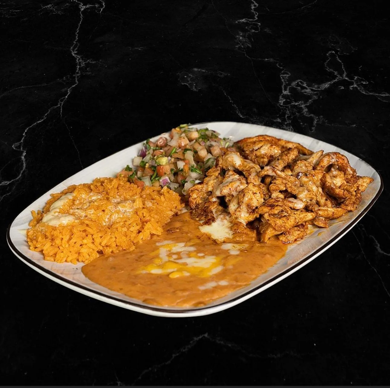 Plate of Mexican chicken fajitas with rice and beans