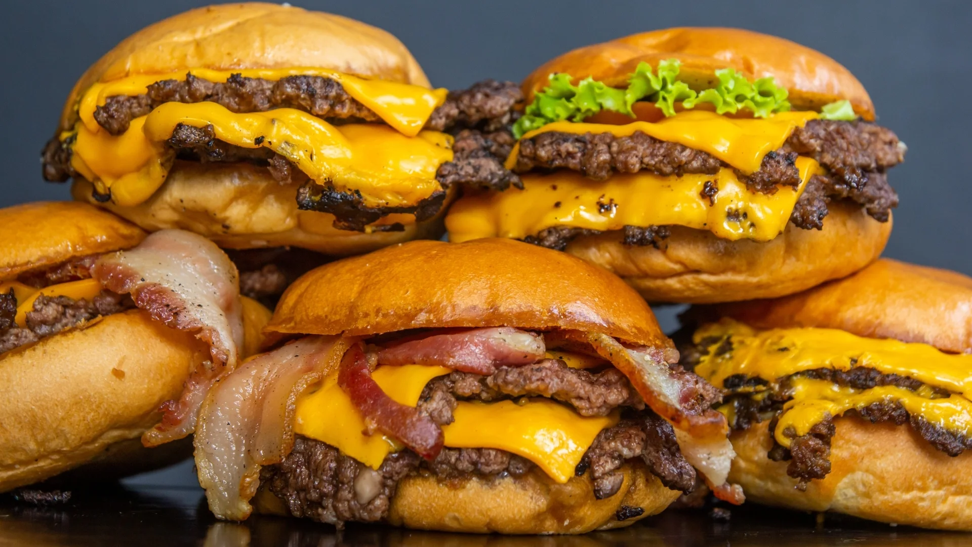 Stack of juicy cheeseburgers with bacon and lettuce