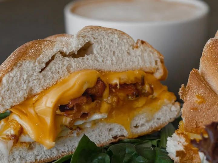 Cheesy breakfast sandwich with bacon on a bed of greens