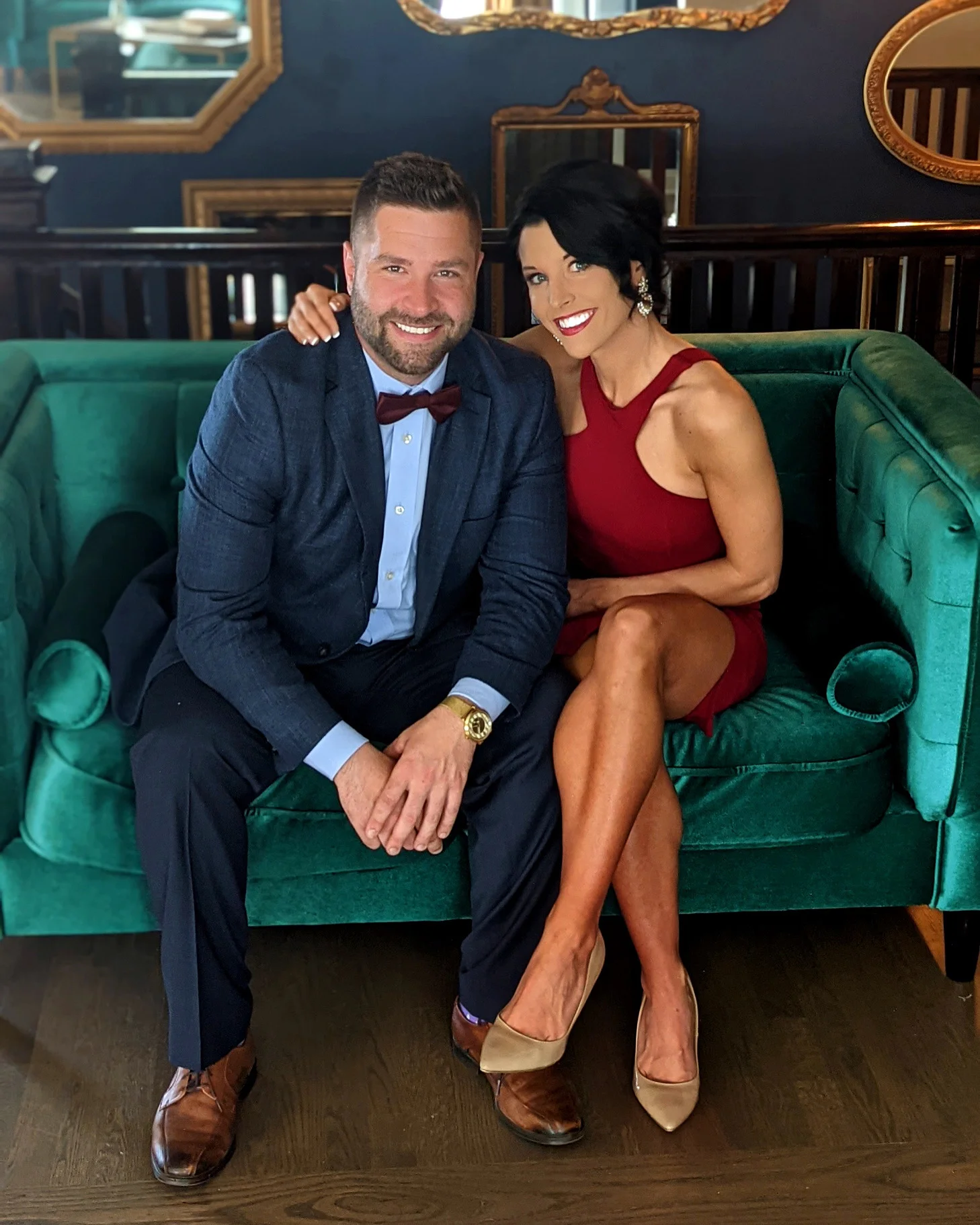 Couple posing on a green velvet couch in a stylish restaurant setting