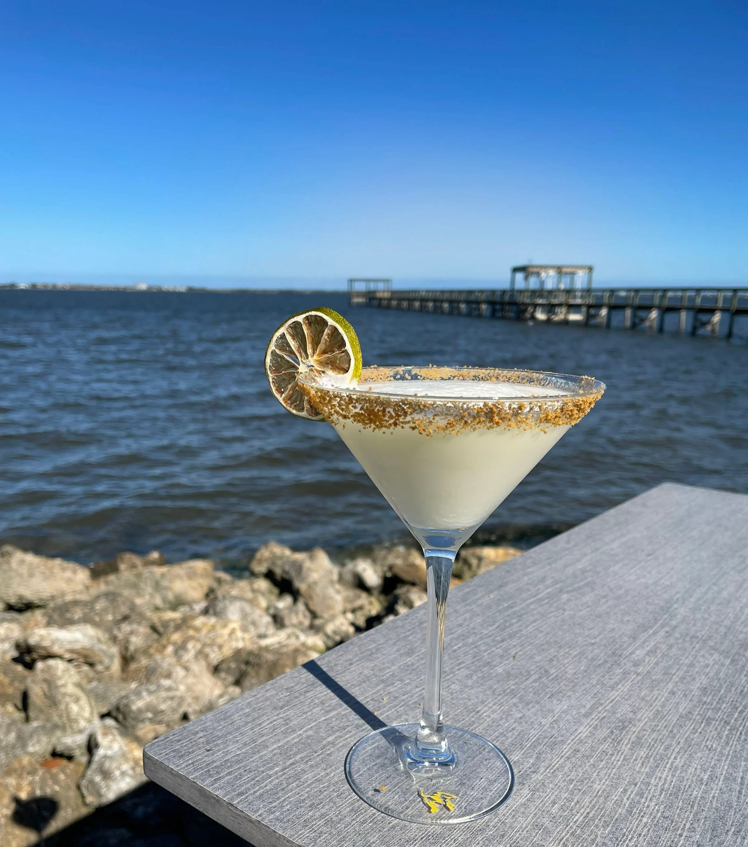 Refreshing cocktail by the water with a lemon garnish