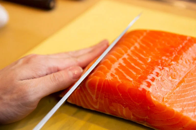 Slicing fresh salmon for sushi preparation