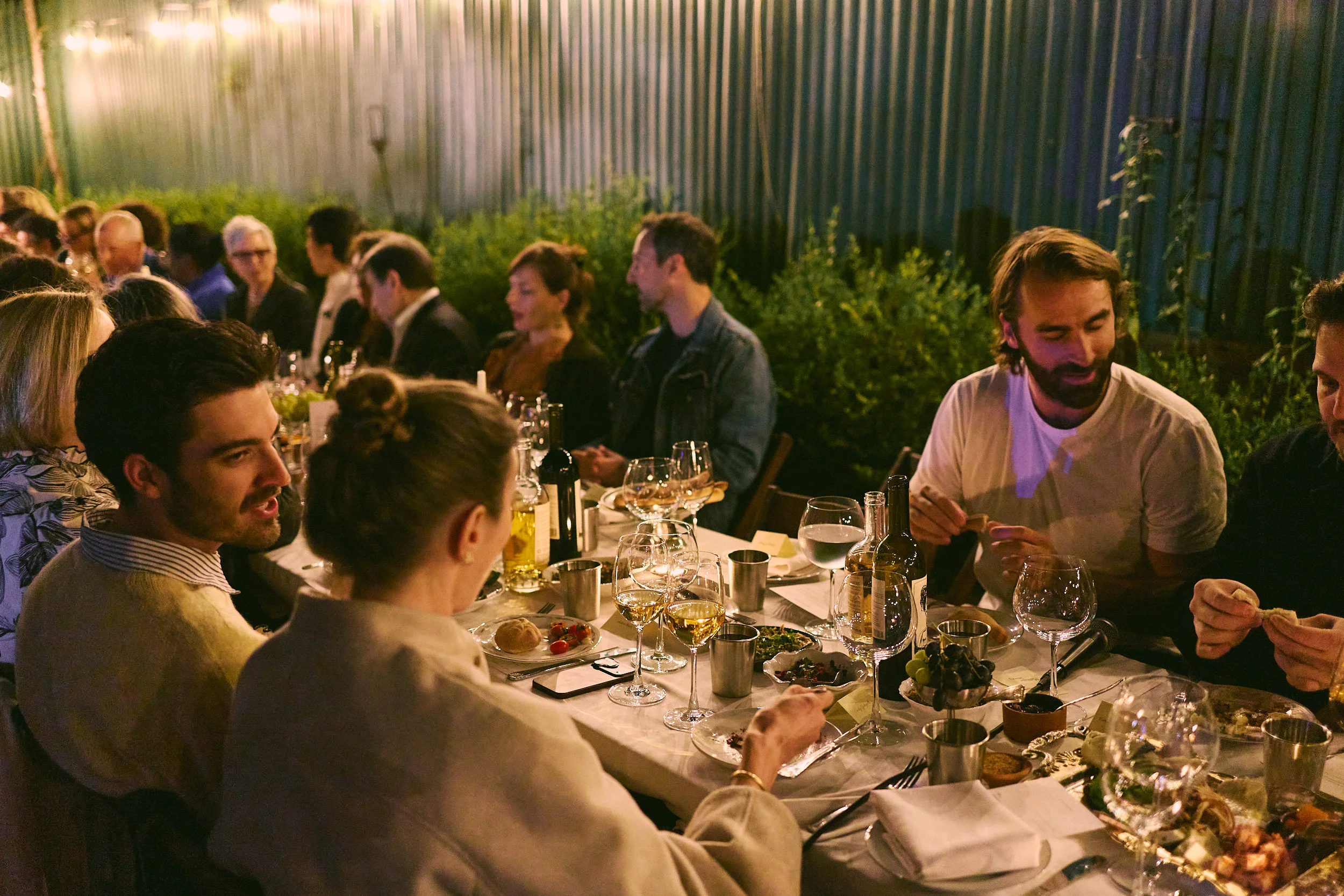 Lively restaurant dining room with guests enjoying dinner and wine