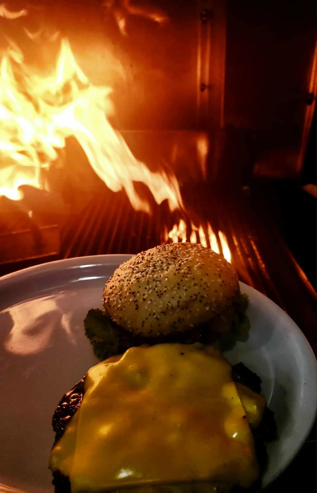 Grilled cheeseburger with smoky flames in the background