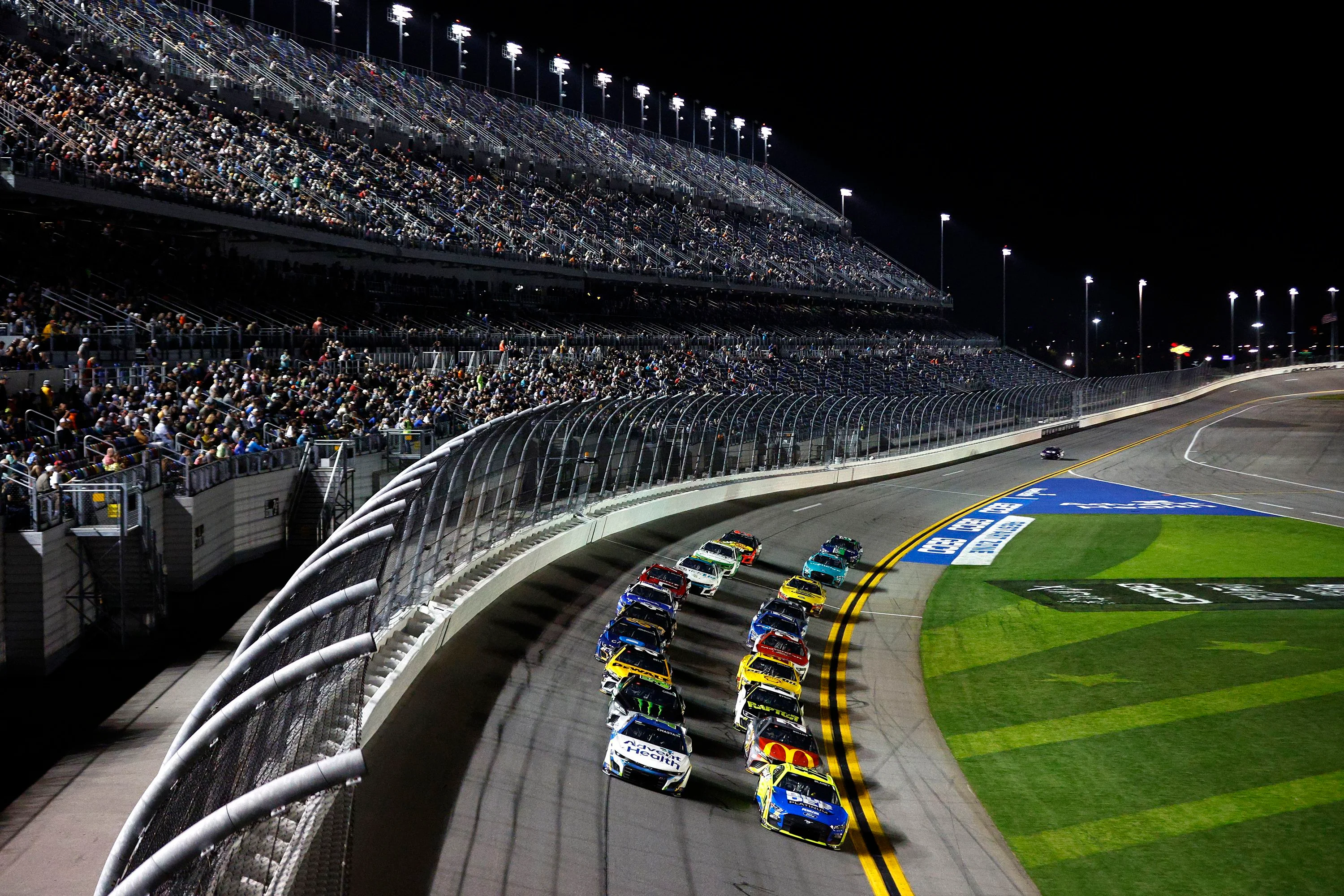 NASCAR race cars competing under stadium lights