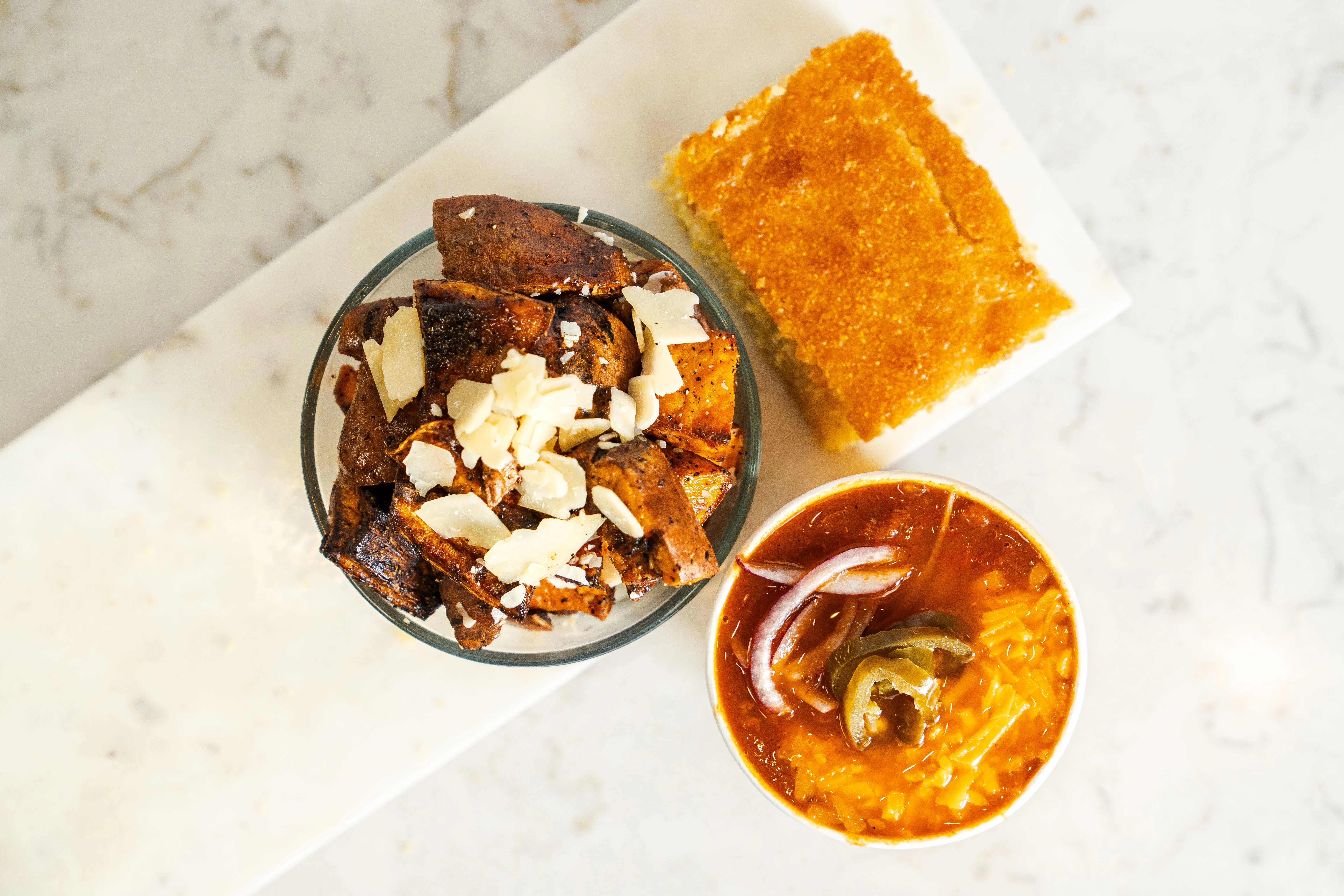 A bowl of spicy rice with toppings, alongside a dish of roasted vegetables and a sweet dessert.
