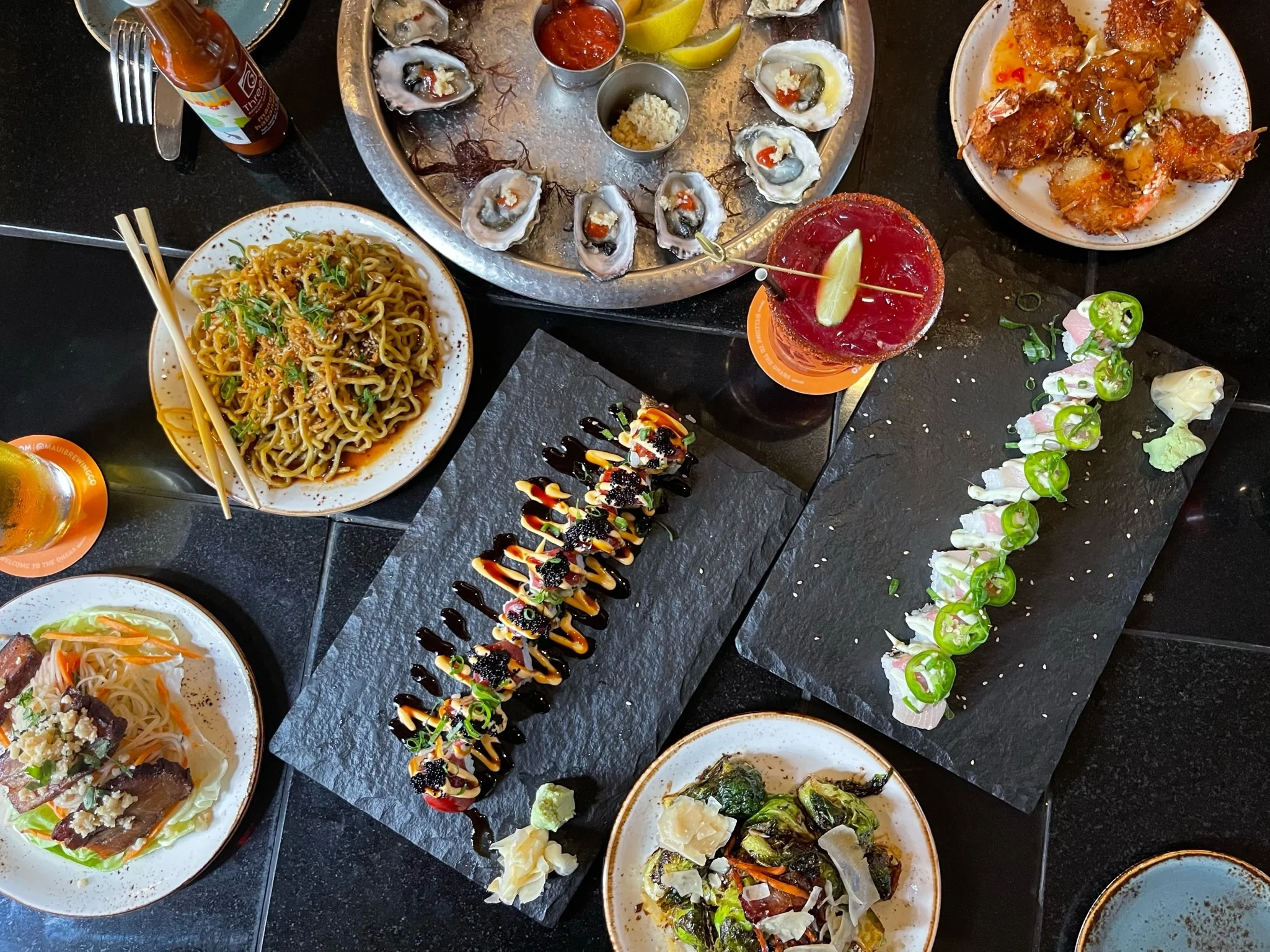 Assorted sushi and Asian dishes on a black table